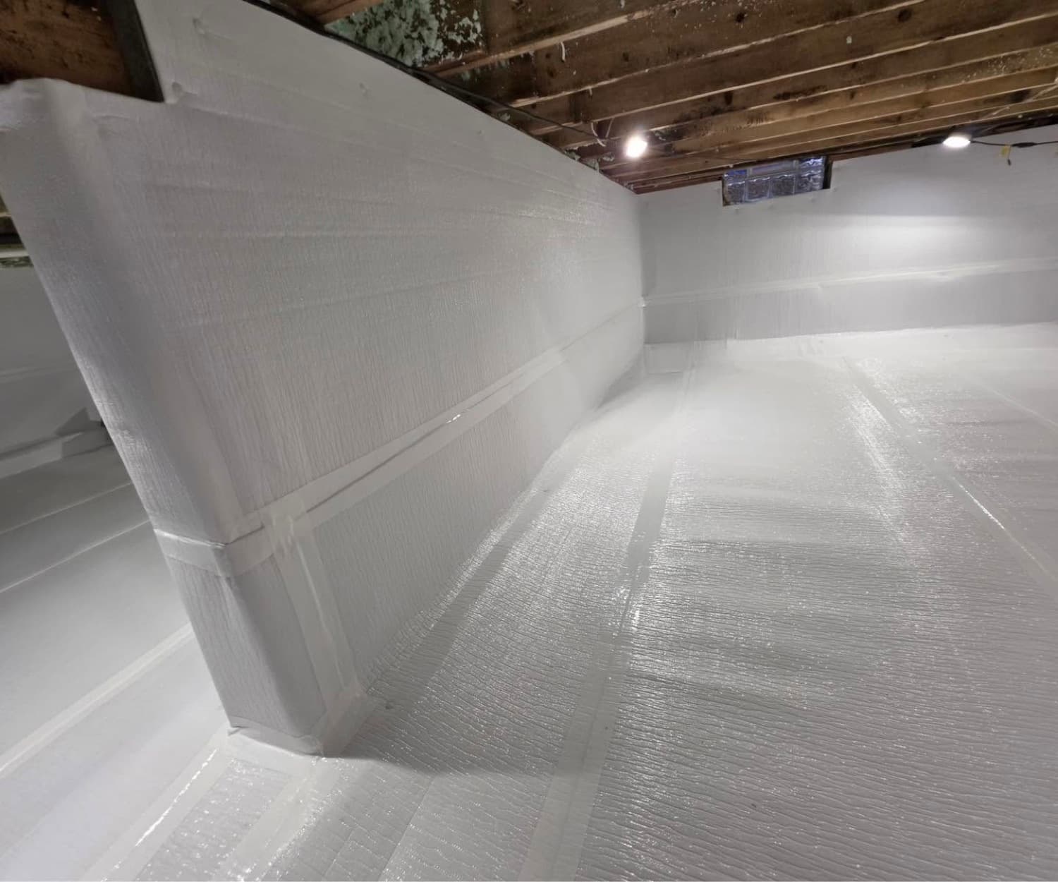 Fully encapsulated crawl space with a bright white heavy-duty vapor barrier covering the walls and floor