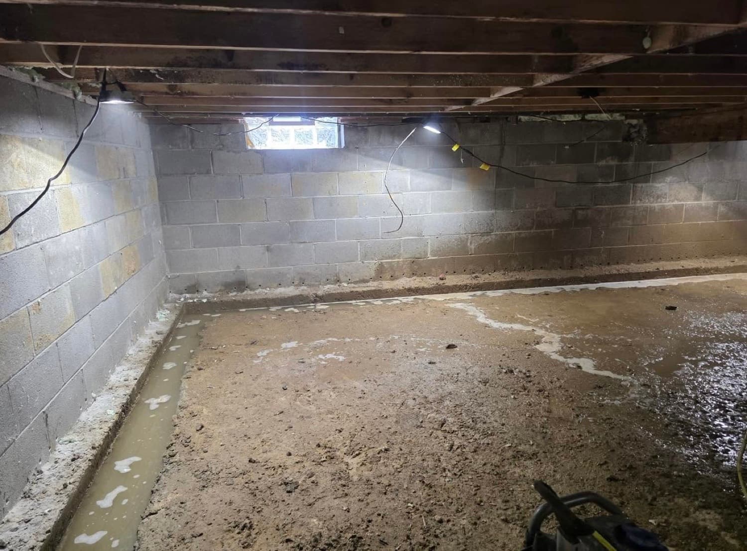 Interior footer drainage trench dug around the perimeter of a crawl space before the vapor barrier is installed