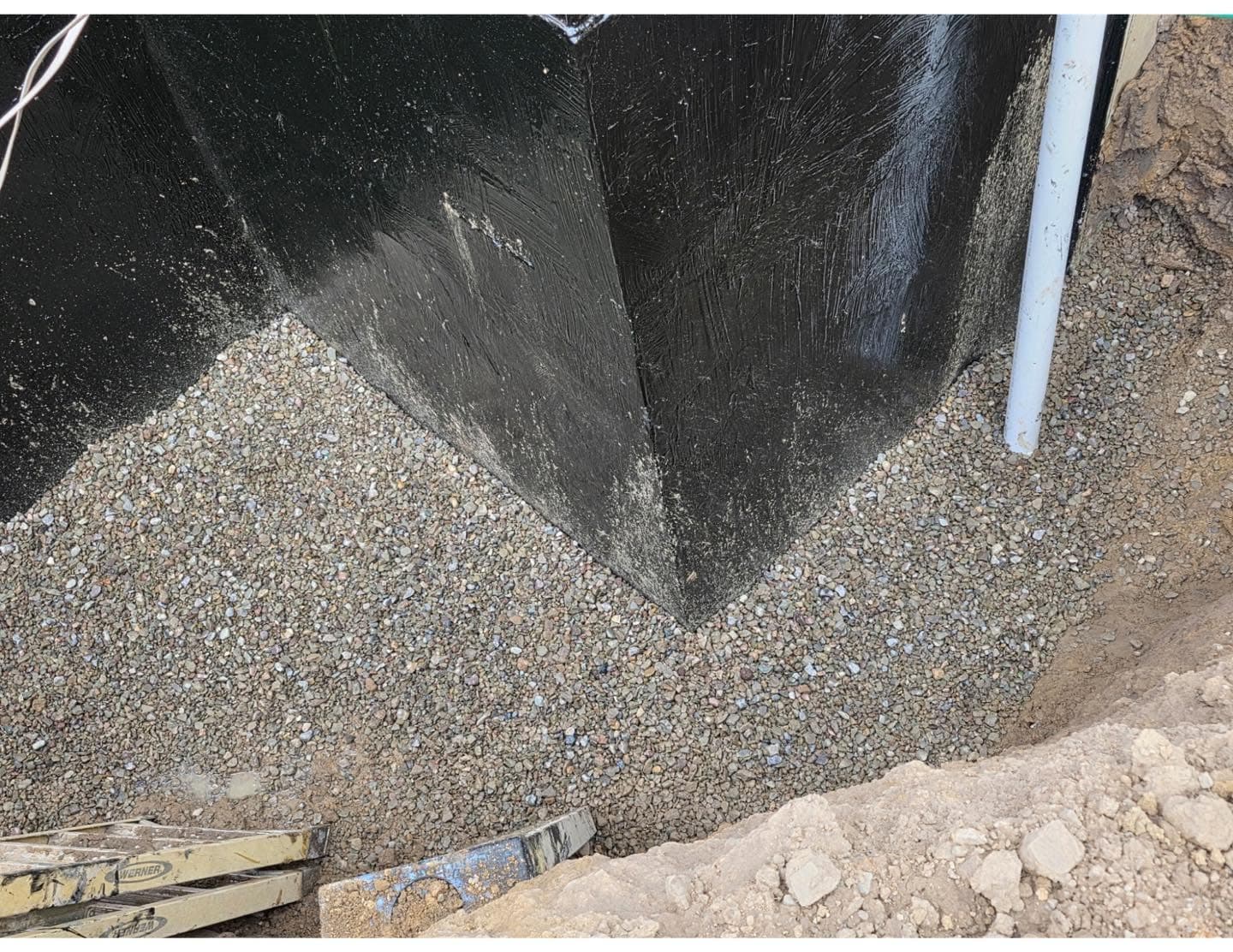 Washed 2B river rock backfilled against a Tremco-sealed foundation wall during exterior basement waterproofing in Western PA